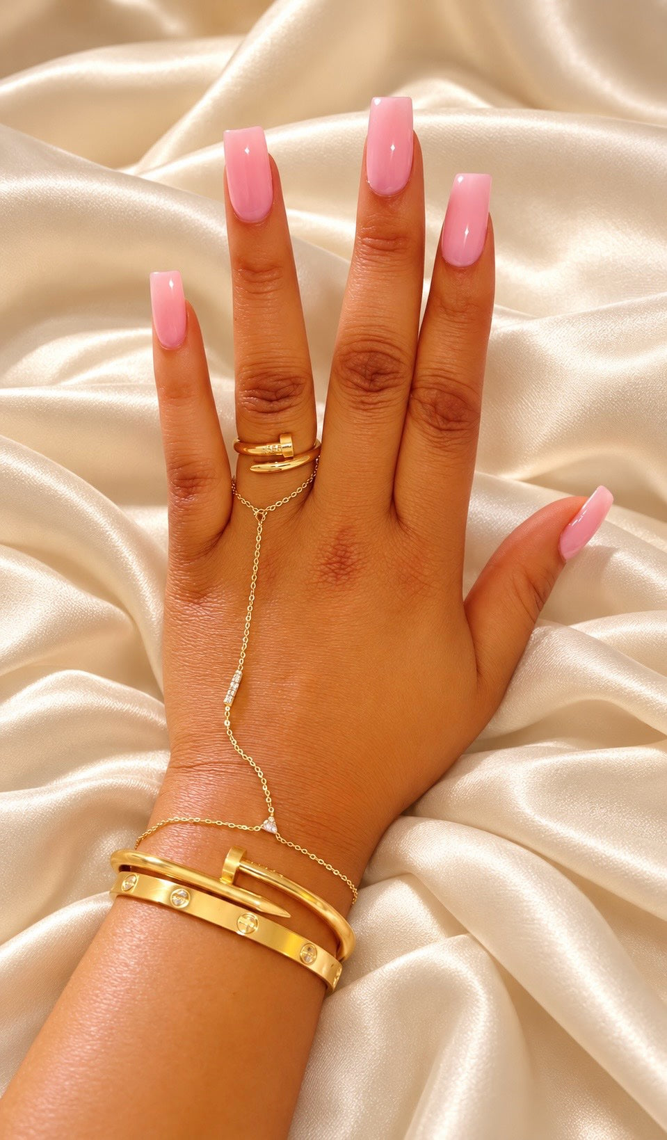 The Mimi Hand Stack — hand with gold ring, hand chain and bracelets on cream silk